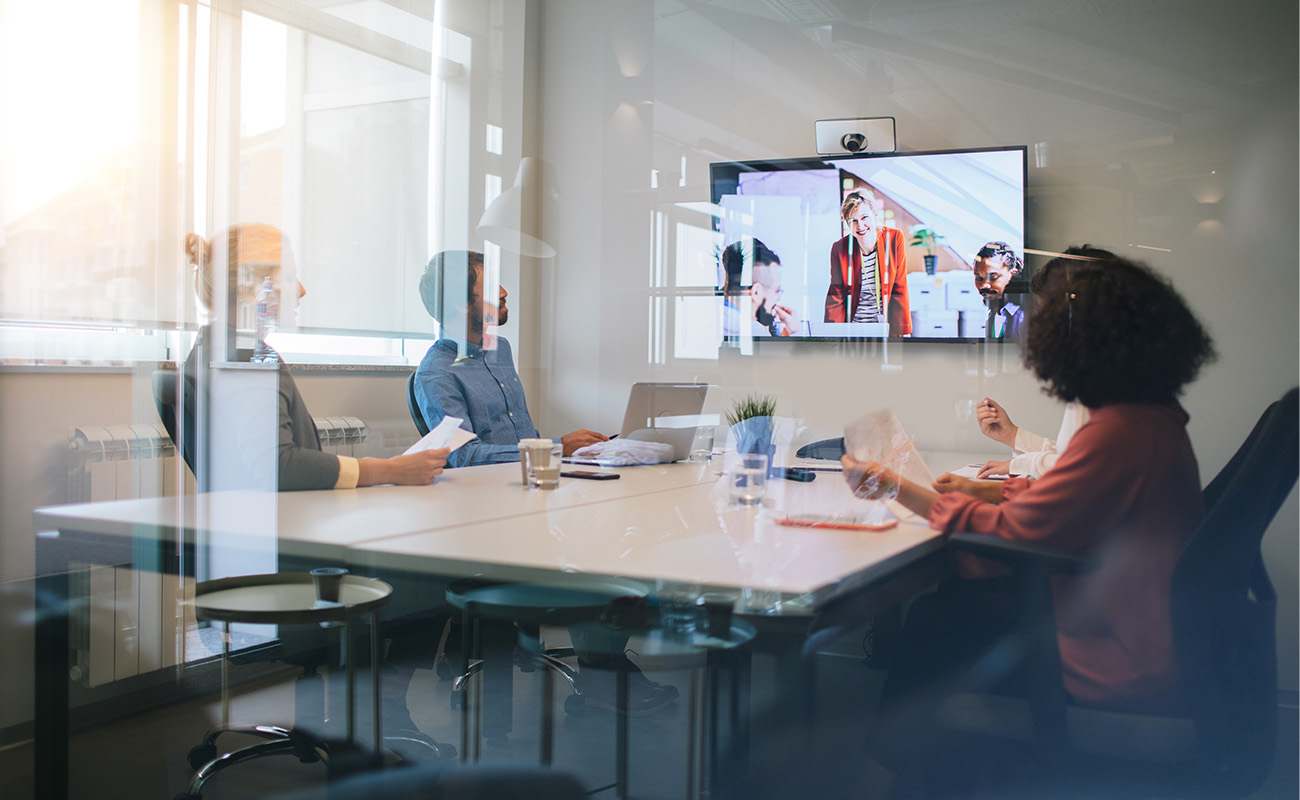 People in conference room looking at virtual meeting